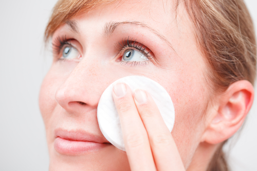 Woman cleansing her face with a cotton pad to help prevent blackheads